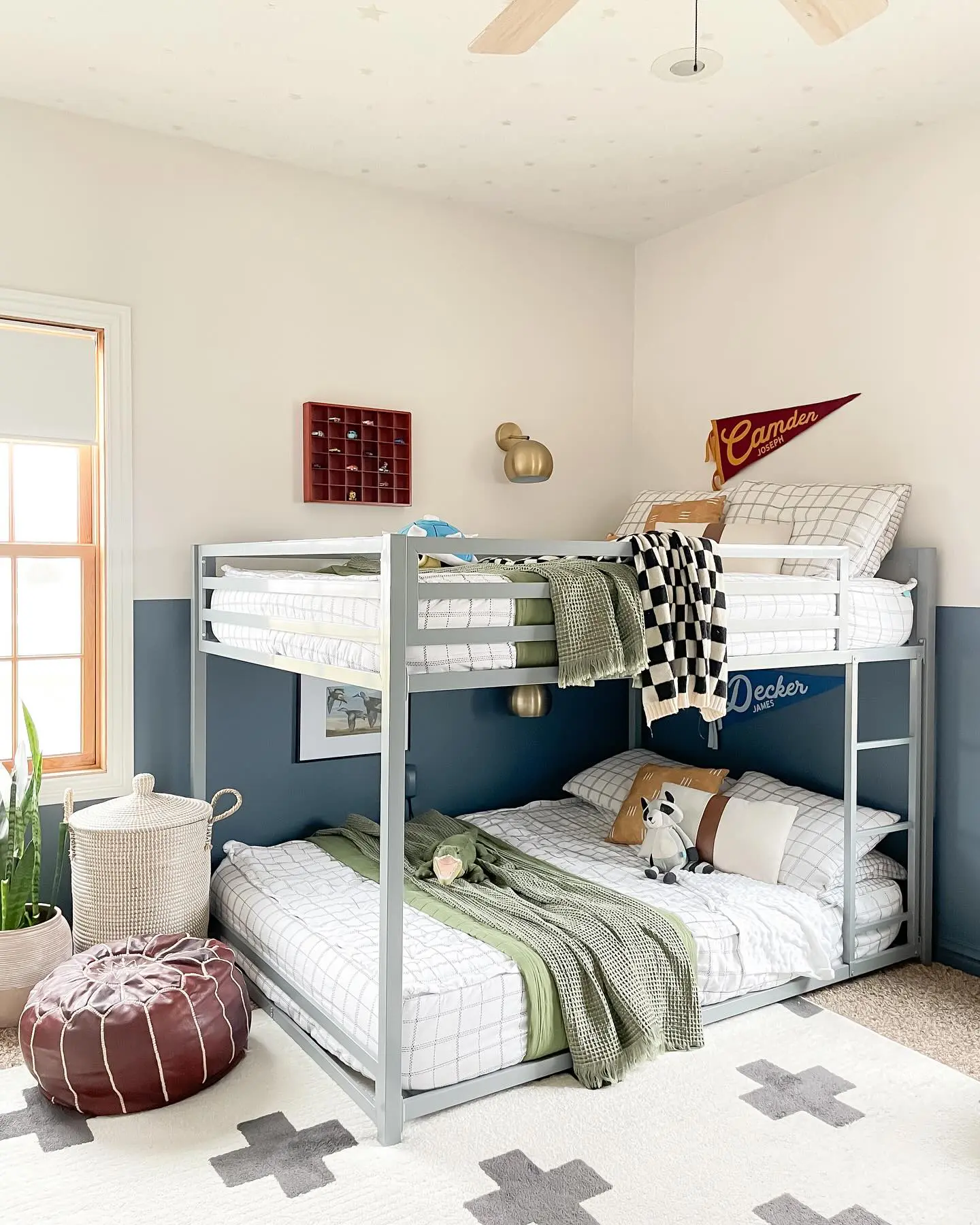 The deep blue paneled walls give the space a bold and moody feel, while the warm wooden furniture and plaid bedding bring in a cozy cabin vibe. The addition of brass sconces adds a touch of elegance, making this an ideal shared bedroom for boys.

(@houseon610th).