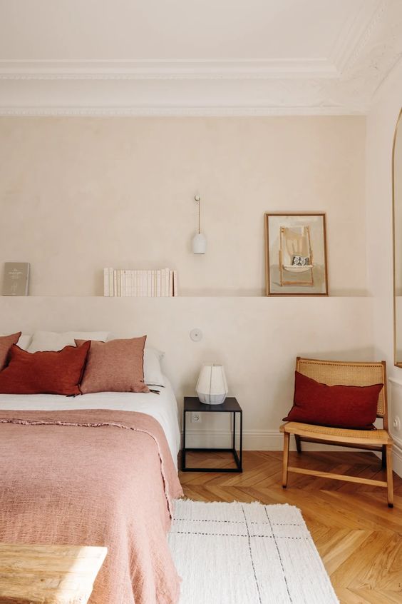 The neutral bedroom done with a tan accent wall that includes a headboard ledge, with decor and books on it.