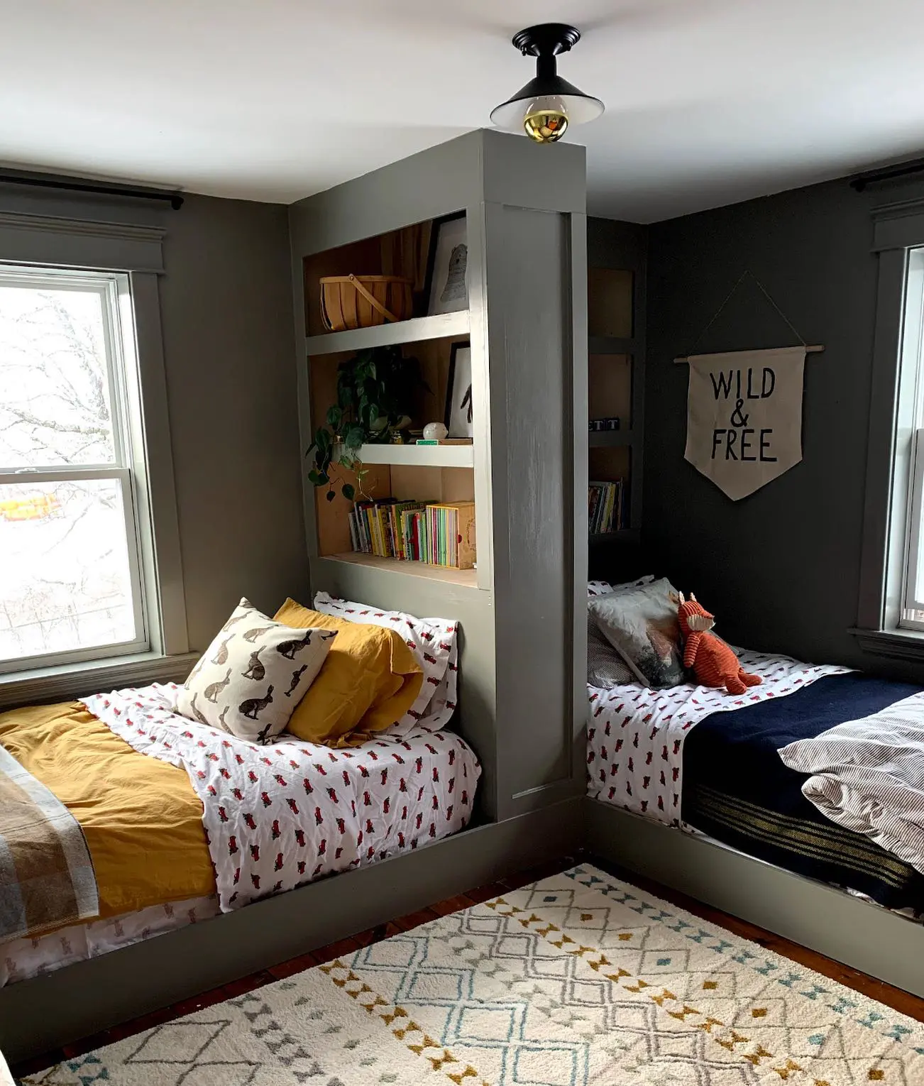 A creative twist on a traditional bunk room, this design features two twin beds with a built-in partition wall, allowing for privacy while keeping the space open and airy. The muted green walls and natural wood tones add warmth, while the cozy textiles and playful accessories make it a stylish and practical setup for a shared boys’ bedroom.

(@maplehouseharvey).
