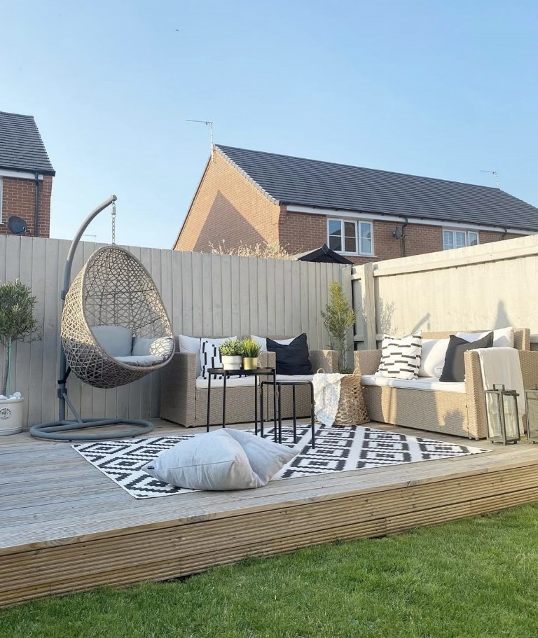 The raised deck is an outdoor living room with comfortable and stylish furniture and some plants.