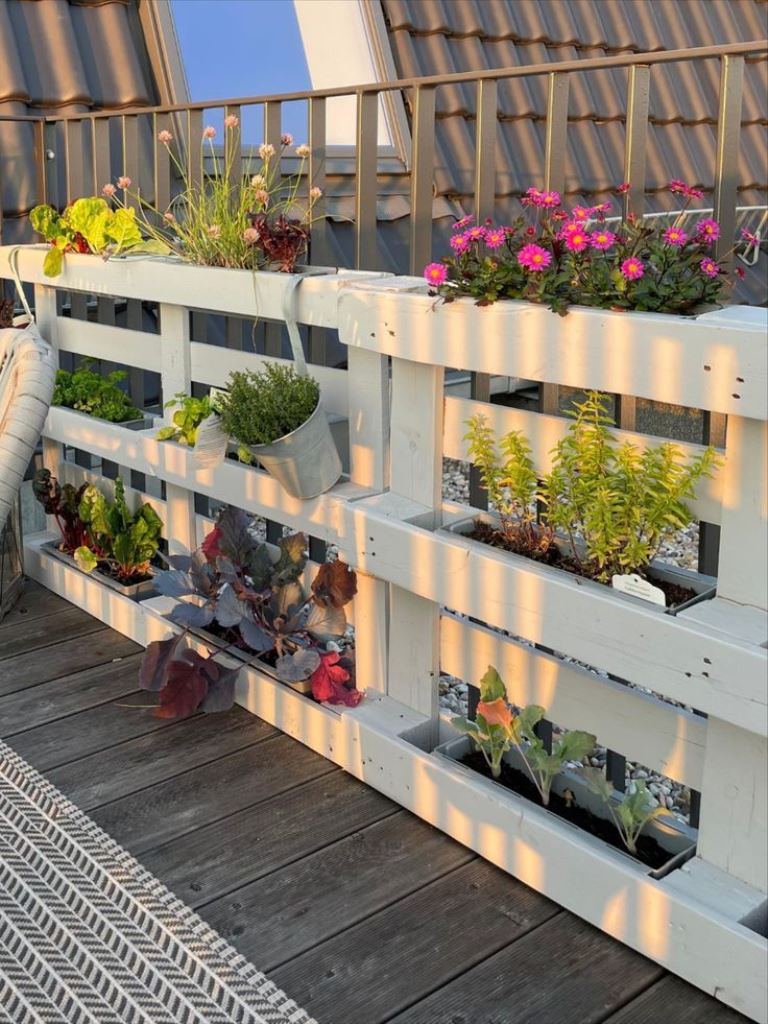 This vertical garden is made of pallets to grow some flowers, and it's a lovely way to style railing or a fence.