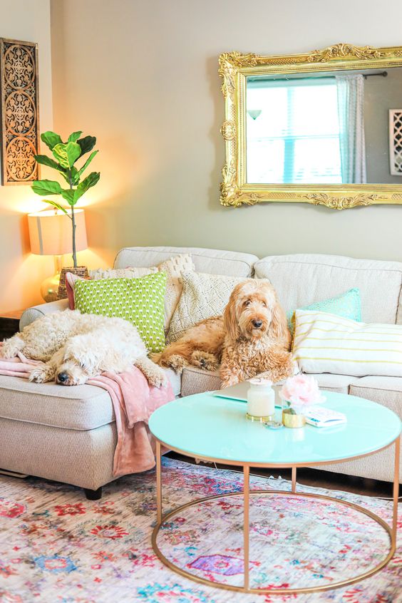 Pastel pillows and blankets, a floral print rug, a turquoise table and pillows for a fun and bold living room.