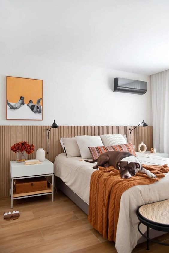 This modern bedroom is done with a bed and an extended ribbed headboard with sconces attached, a nightstand, a cane bench.