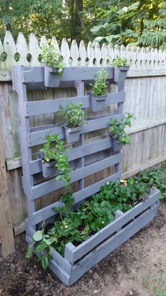 The pallet is painted grey and transformed into a plant stand and a vertical garden with planters.