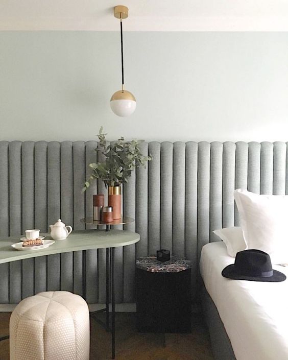The serene bedroom is done with a grey upholstered ribbed headboard that adds texture and a trendy feel to the space.