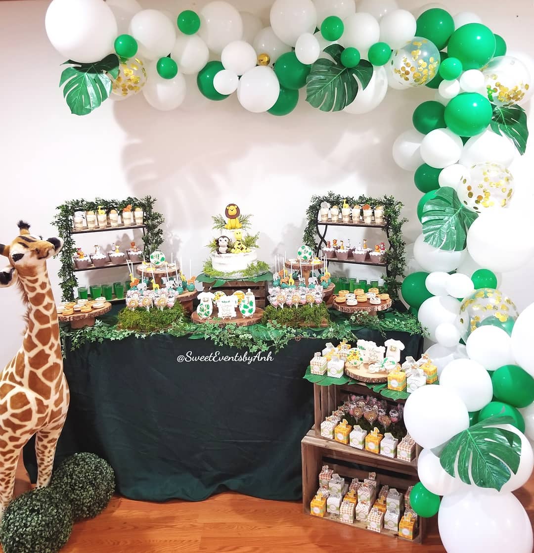 Get wild with this adorable jungle-inspired table featuring balloon vines, leafy greenery, animal cake pops, and a plush giraffe welcoming guests to a baby shower safari.

(@sweeteventsbyanh).
