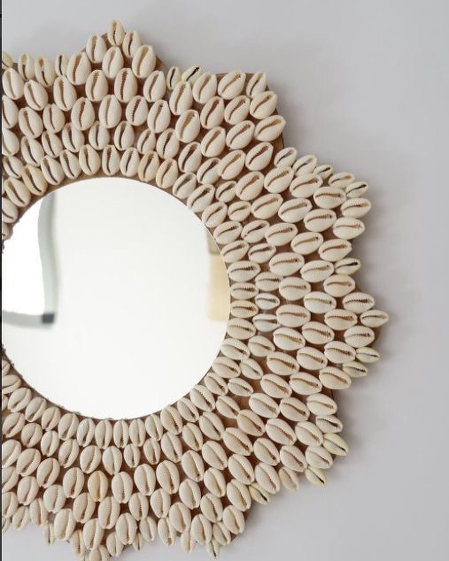 A round mirror becomes a stunning coastal statement piece with cowrie shells intricately layered into a bold, sunburst-like design.

(@mirrorssandmore).