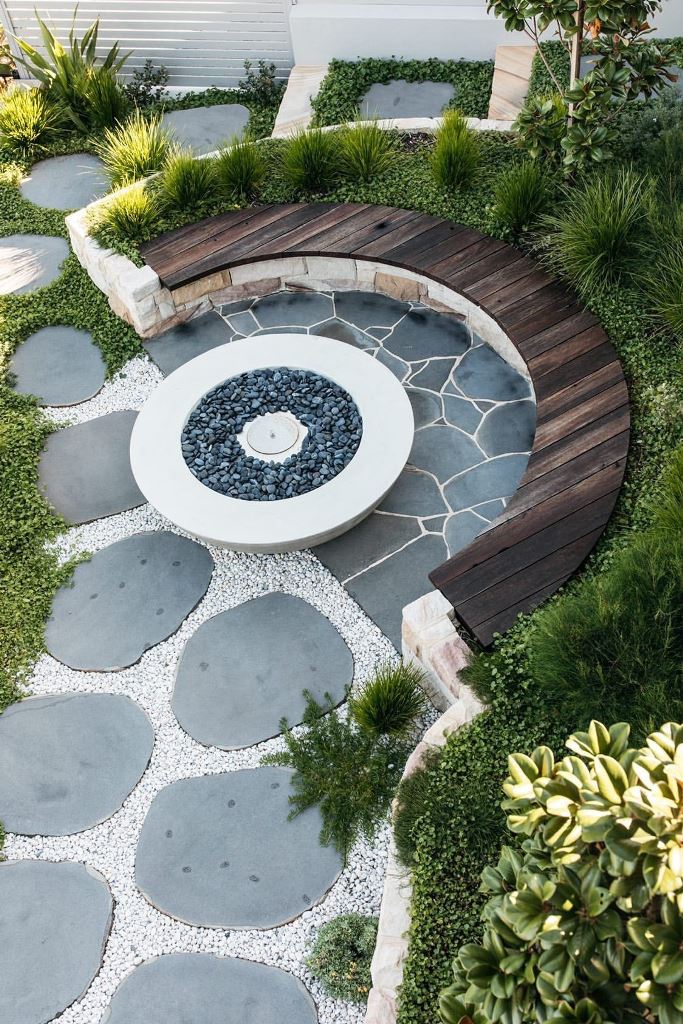 The patio is clad with natural stone, and the semi-cicrcle bench is placed around the fire bowl.