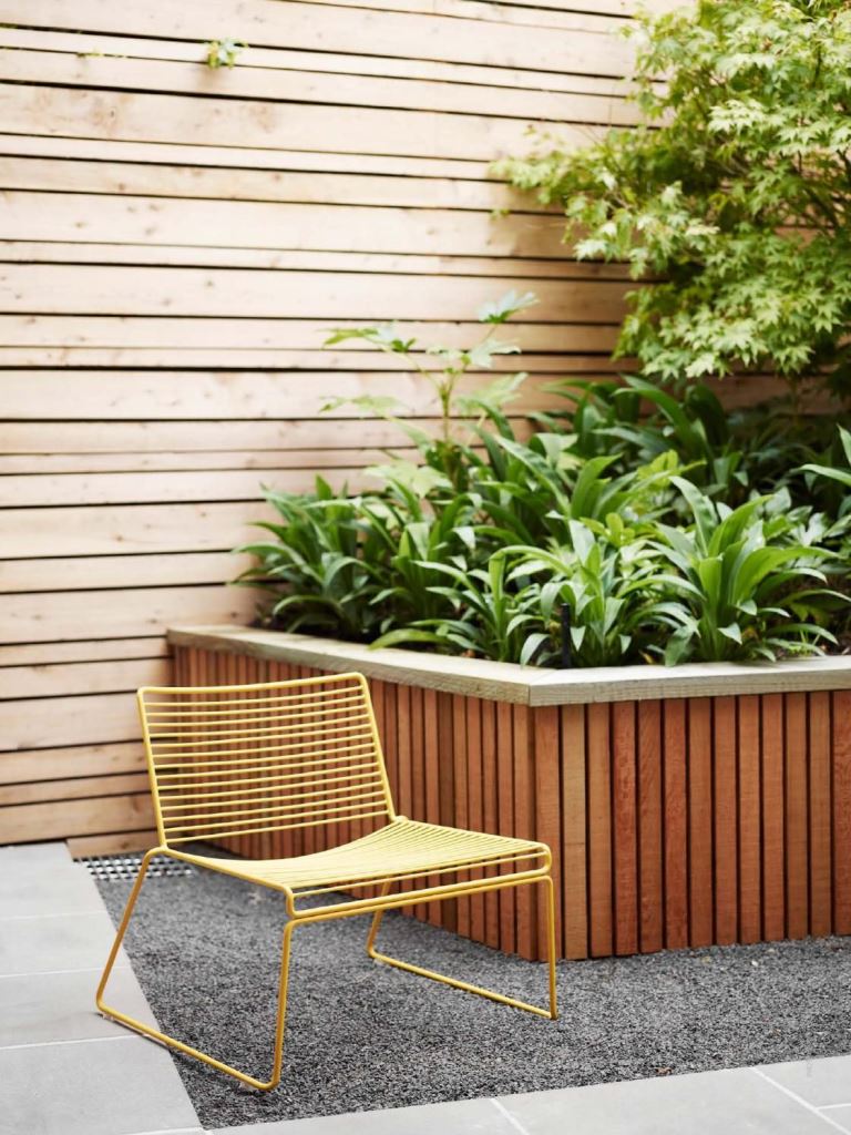 This garden bed features a slatted edge, and greenery inside makes it look even more modern.