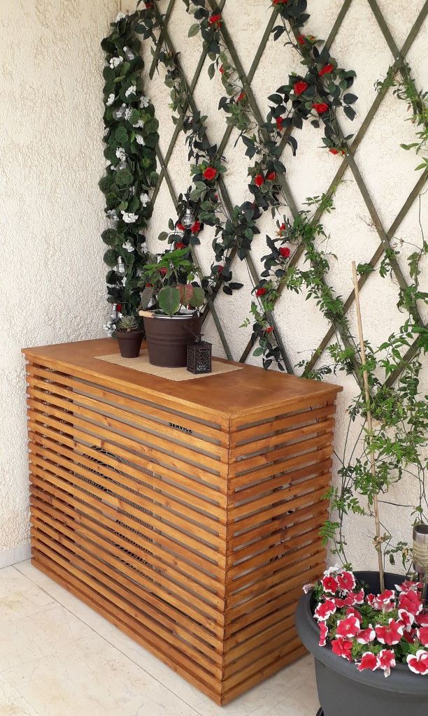 The tall slatted box in the corner is a plant stand and a table, and the AC unit is well-covered.