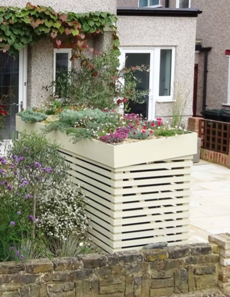 The large slatted box for several trash cans is covered with a large tray with bright flowers.