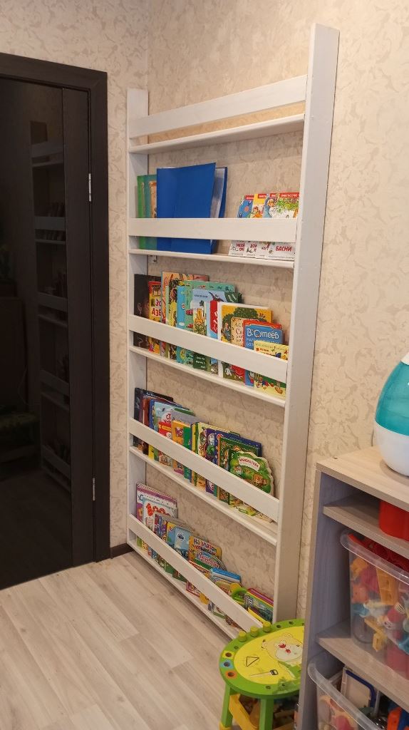 This very narrow and sleek shelving unit is placed in a kid's room to place the books.
