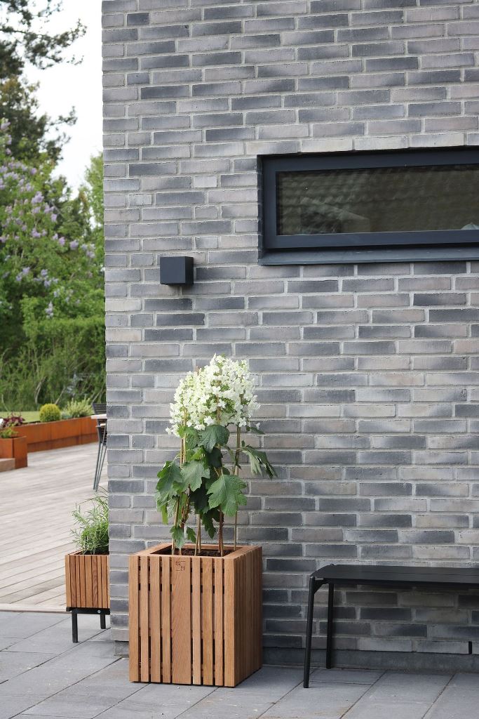 This small slatted pot with blooms refreshes the patio and the grey brick wall.