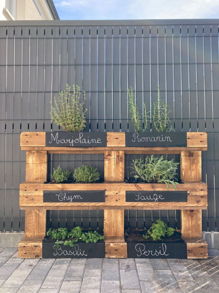 This rustic vertical garden shows off chalkboard marks and various types of herbs.