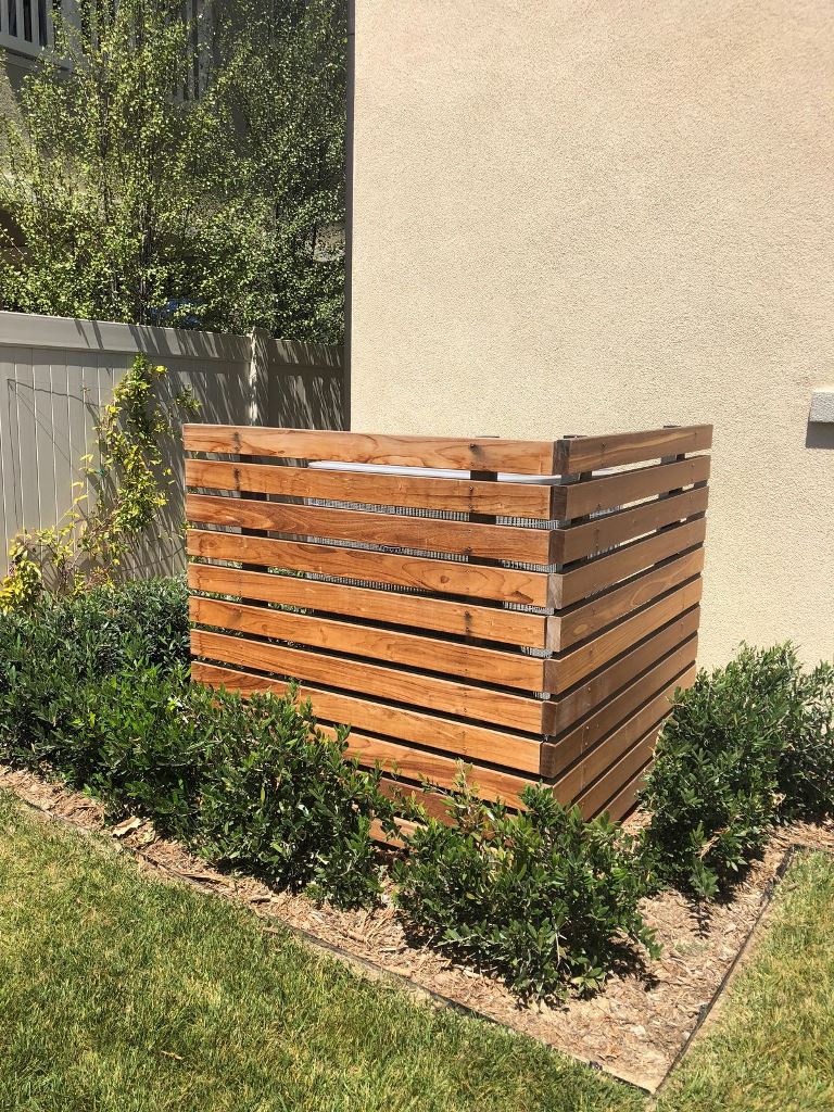 Stained screens are surrounded with greenery to make the AC unit hidden in a cohesive way.
