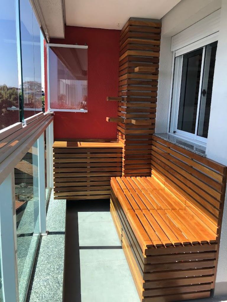 The small balcony is fitted with slatted furniture pieces including a table that covers an AC unit.