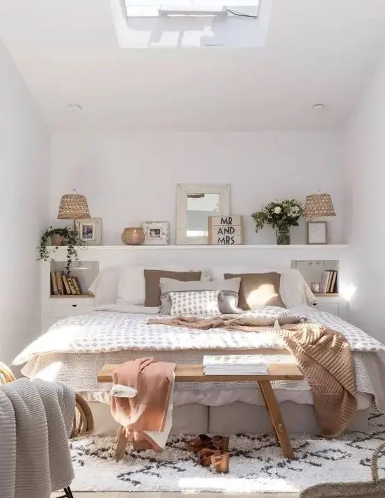 This small space is made more functional with a storage headboard with niches and built-in drawers plus decor on top.