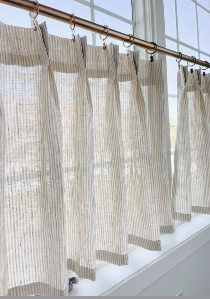 The window is covered with striped cafe curtains that elegantly hide the view.