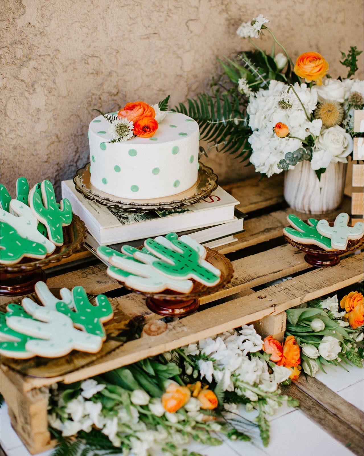 This sweet setup blends charming cactus cookies and a polka-dotted cake with earthy textures like wood pallets, fresh florals, and stacked books for a modern southwestern baby shower vibe.

(@inspiredbythis).