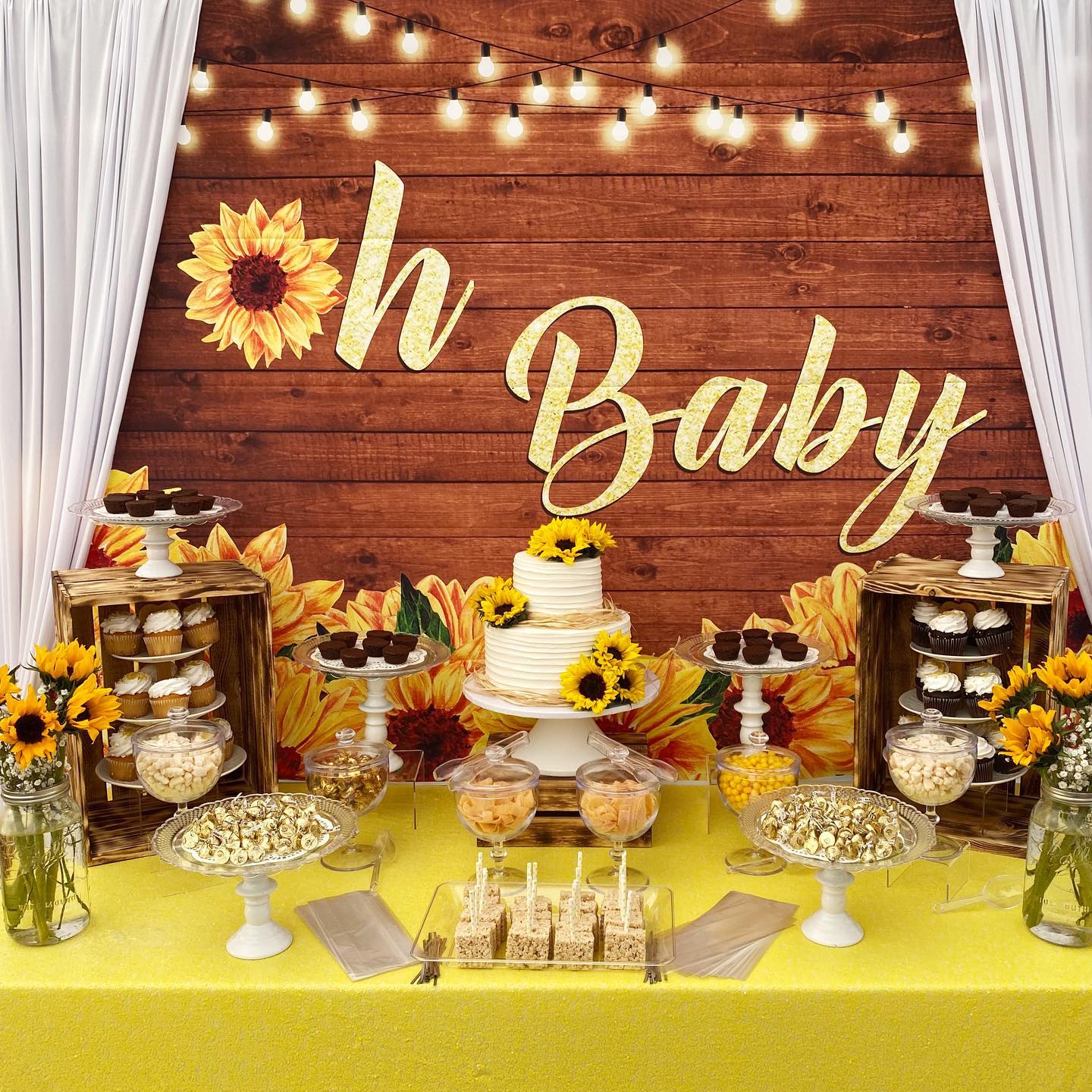 Bright and cheerful, this sunflower-themed dessert table pops with warm yellow tones, rustic wood crates, and twinkling string lights—perfect for a sunny baby shower celebration.

(@nettiescakecreations).
