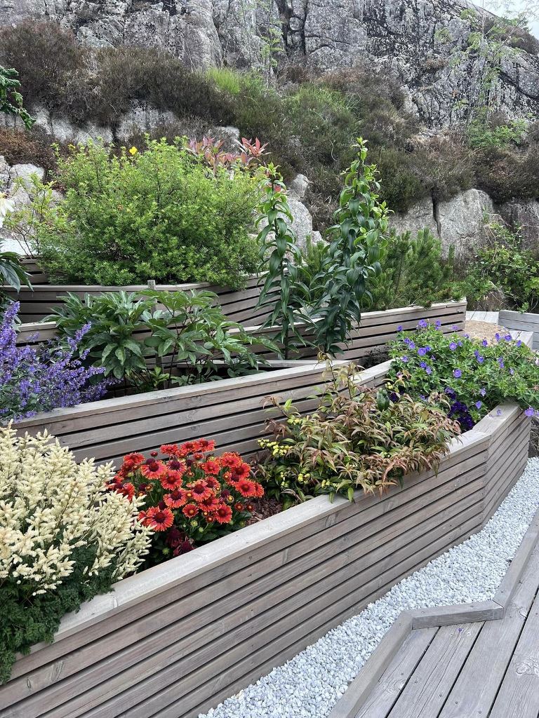 The tiered garden is composed of multiple slat garden beds with bright flowers.