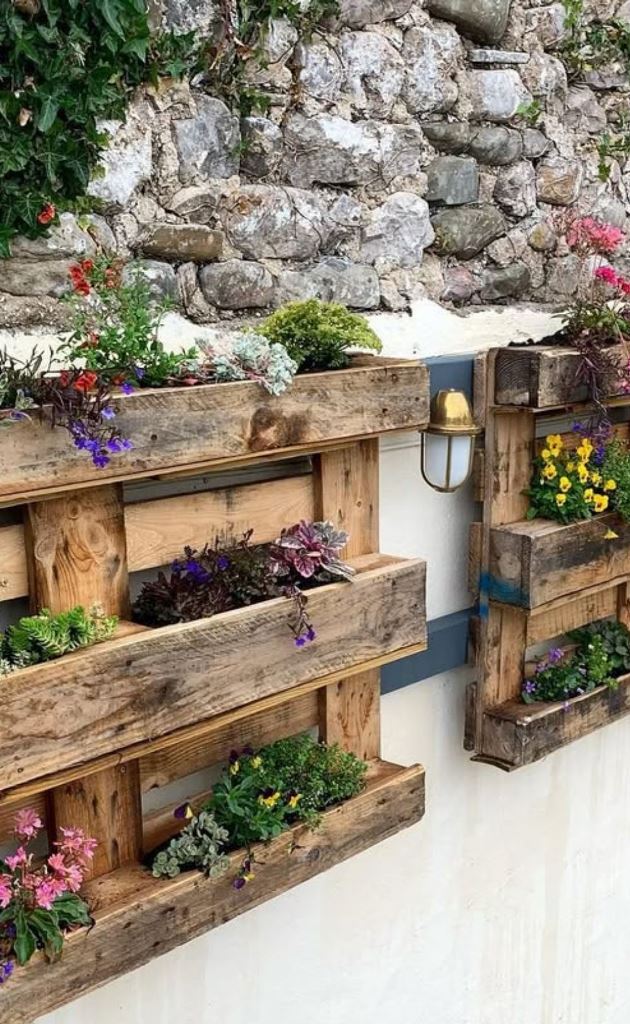 Stained pallets are a floating garden on the fence, and various blooms refresh the space.